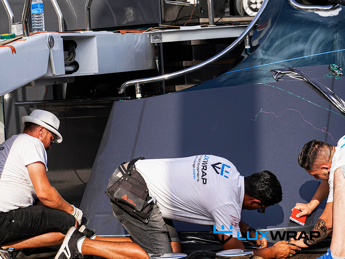 LuxWrap installers applying marine vinyl wrap to superyacht hull during refit transformation