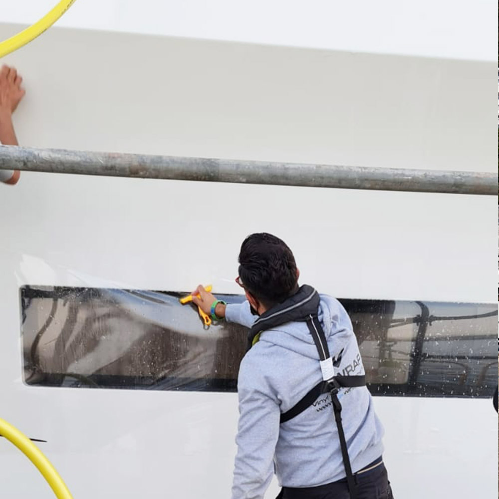 LuxWrap installer applying clear gloss paint protection film to the hull of a 110m Feadship superyacht