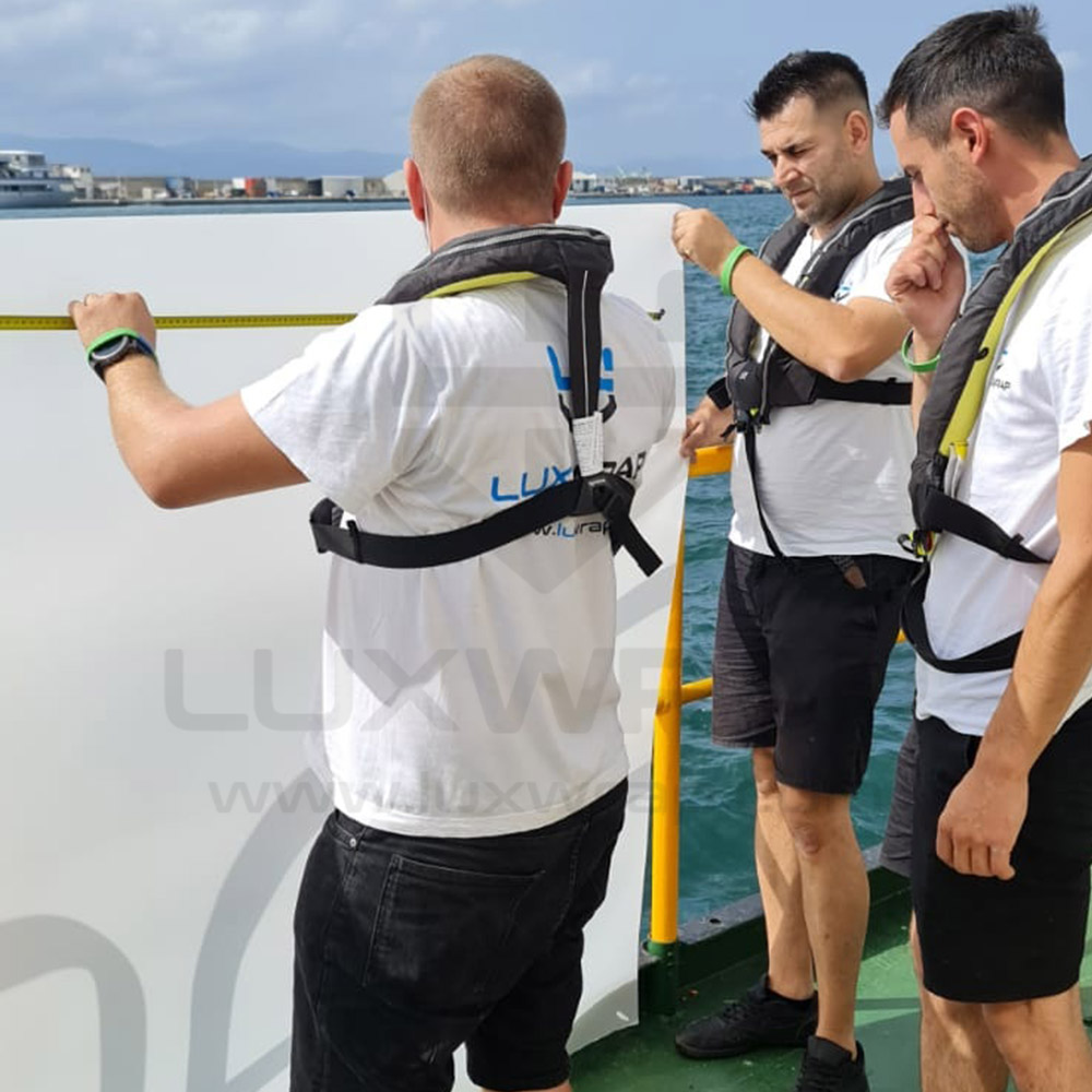 Two LuxWrap team members discussing PPF installation progress on a 110m Feadship superyacht dockside