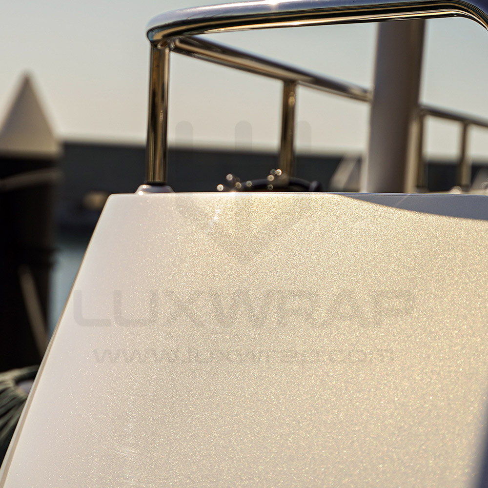 Hull wrap in progress on a 43m Heesen superyacht — metallic white vinyl fitted along the waterline by LuxWrap