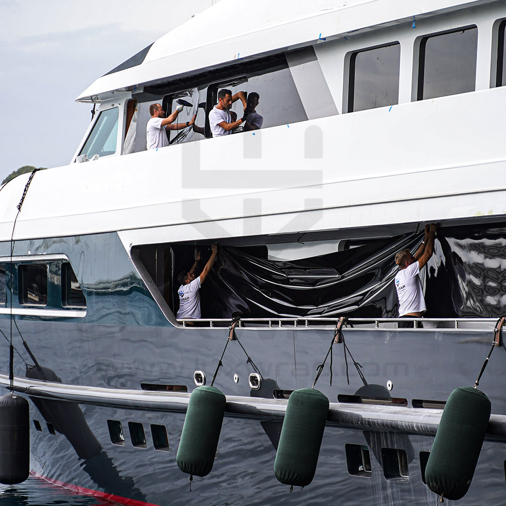 LuxWrap installer trimming anthracite vinyl along the hull of a 47m Swiftships superyacht