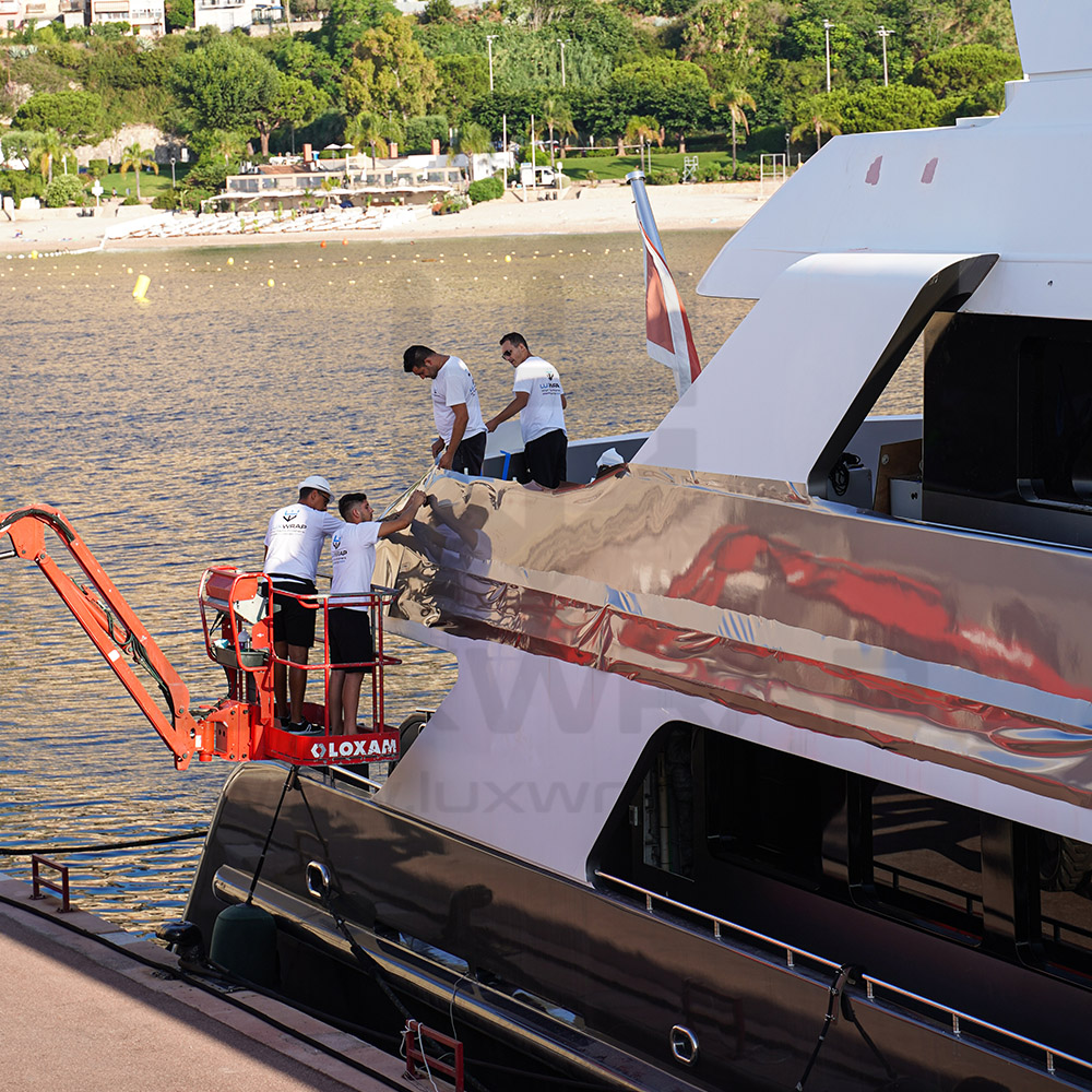 LuxWrap specialist applying black accent vinyl between windows on a 47m Swiftships to extend the glazing line