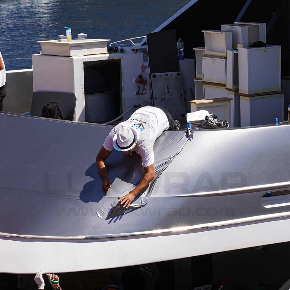 LuxWrap installer fitting silver vinyl to the upper superstructure of a 47m Swiftships superyacht