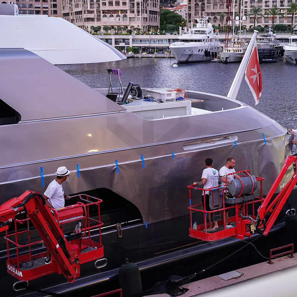 47m Swiftships hull wrap detail — anthracite vinyl fitted along the waterline by LuxWrap from floating rafts