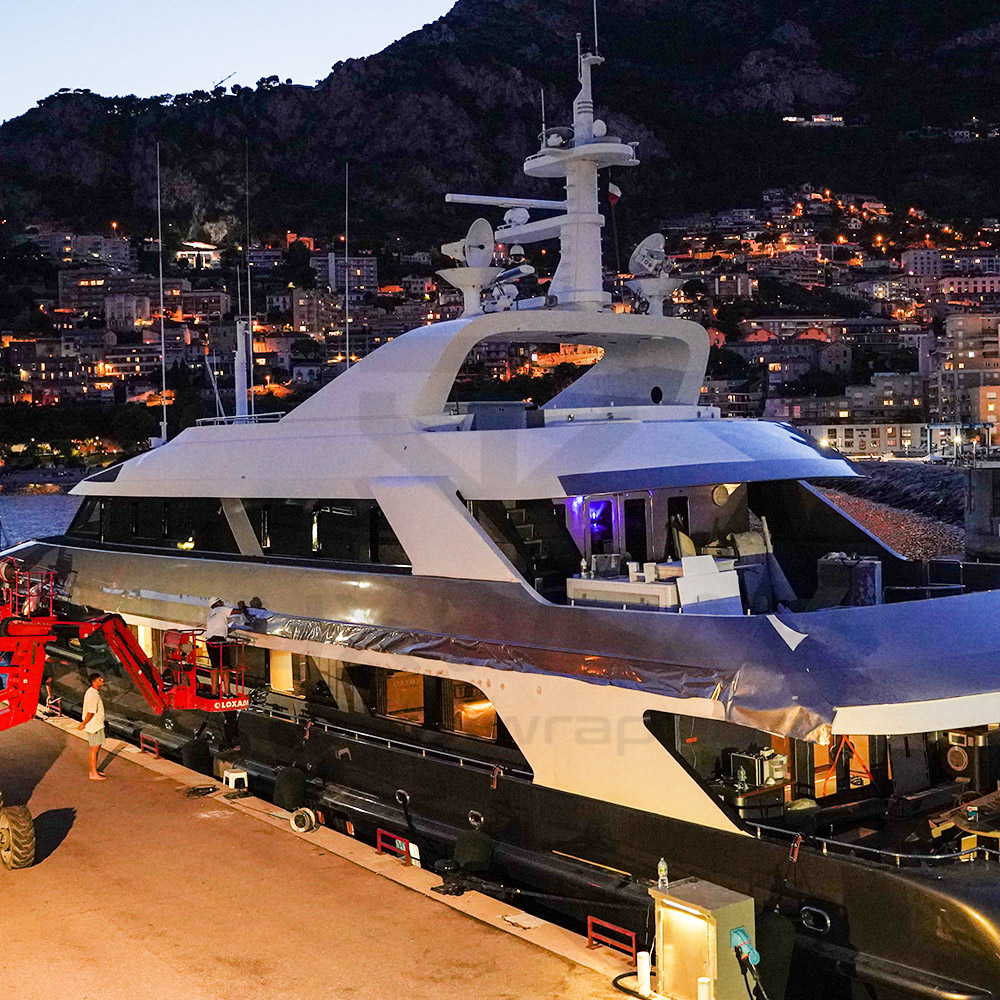LuxWrap installer applying anthracite vinyl to the bow section of a 47m Swiftships superyacht