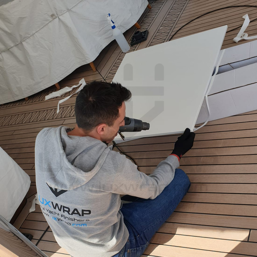 LuxWrap installer applying satin-white vinyl to overhead deckhead panels on a 57m Benetti superyacht