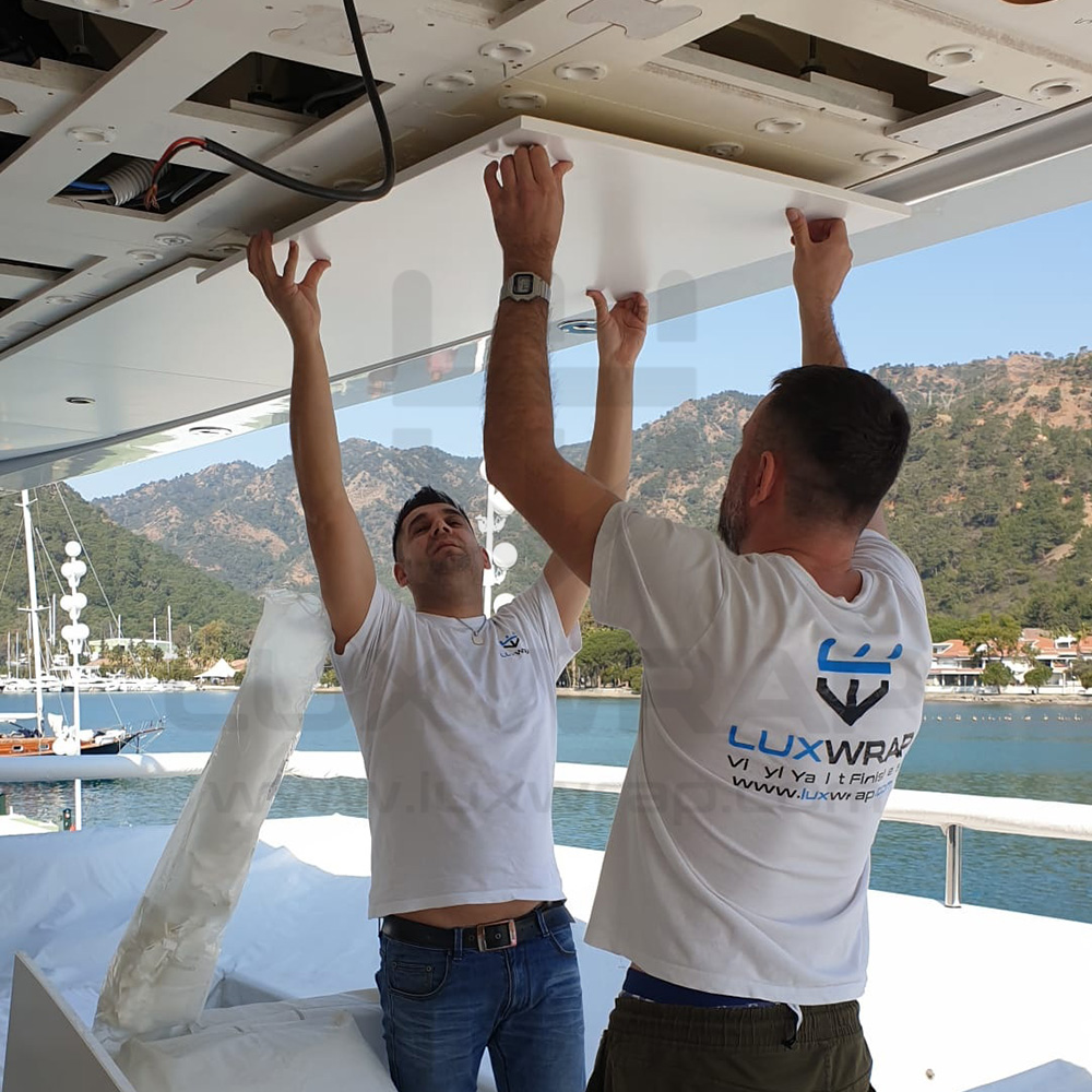 LuxWrap specialist fitting satin-white vinyl to deckhead panels on a 57m Benetti superyacht interior